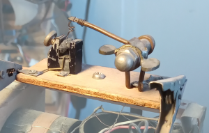 close up image of a crystal detector, made of a pea-sized fragment of Galena (lead sulfide) mounted on a metal clamp, and being touched by a thin wire mounted on a swivelling arm to allow adjustment.